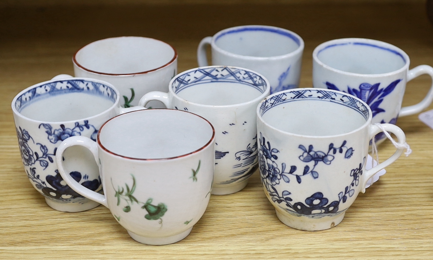 Seven various English porcelain coffee cups, including two Bristol enamelled with green floral sprays, two Bow painted in underglaze blue with a bird in a Chinese garden, and three Worcester/Bow in underglaze blue.